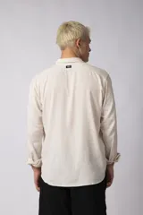 Camisa color crudo de lino con caída liviana y calce relajado, cuello abierto y manga larga. Confeccionada en 70% rayón y 30% lino.