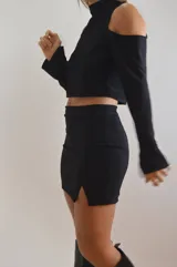 Mini falda negra de diseño ajustado con detalles asimétricos y brilante.