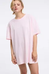 Remera rosa holgada con estampado de texto en el frente.