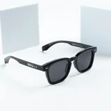 Lentes de sol negros con marco cuadrado y cristales grises.