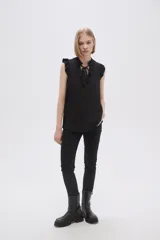 Blusa sin mangas color crudo con cuello con lazo y volados en los hombros.