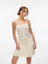 Top de tejido de punto color blanco hueso, con tirantes finos y escote cuadrado ribeteado con ondas. Presenta una hilera de botones frontales.