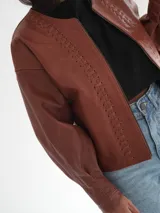 Campera oversize de cuero color marrón con cierre frontal y detalles de costuras en los bordes.