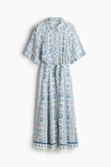 Vestido midi con estampado floral en tonos celeste y azul, cuello camisero, botonadura frontal, mangas cortas raglán, elástico en la cintura y cinturón extraíble para atar.