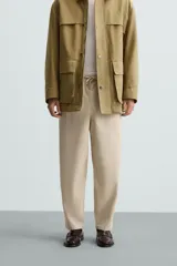 Pantalón verde militar de corte carrot fit, confeccionado en tejido de algodón. Cuenta con cintura elástica ajustable con cordón, bolsillos frontales y un bolsillo trasero de plastrón.