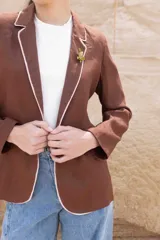Blazer color chocolate de lino con solapas con borde en contraste color beige, cierre con un botón y corte entallado.