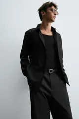 Camisa negra de manga larga con cuello italiano y cierre frontal de botonadura. Presenta un tejido con estructura de fácil cuidado.