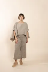 Poncho color beige con diseño a cuadros, cuello bote y terminaciones desflecadas. Tiene aberturas para los brazos en los laterales y detalles en cuero.