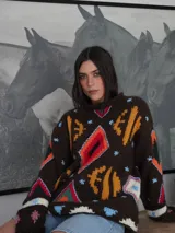 Sweater tejido a mano en lana color marrón con intarsia y bordados multicolores. Diseño único con combinaciones de colores variadas. Cuello alto y mangas largas.