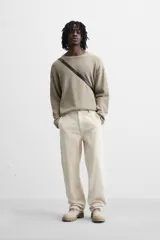 Pantalón de pana color crema, corte relaxed fit, con bolsillos frontales, bolsillos de parche en la parte trasera, bolsillos laterales en las piernas, trabilla multifunción y cierre con cremallera y botón.