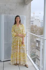 Vestido largo amarillo con estampado floral blanco, cuello en V, mangas 3/4 y corte escalonado.