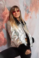 Chaqueta de cuero plateada con acabado metalizado y diseño acolchado. Presenta cuello y puños de piel en color negro, cierre frontal metálico y bolsillos laterales con cremallera.