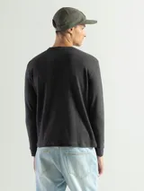 Remera negra de manga larga con cuello redondo, confeccionada en tejido mini piqué de algodón.