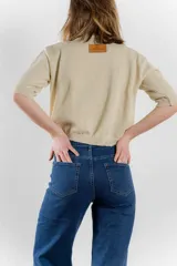 Sweater color dorado de tejido de punto suave con hilos metalizados, corte recto y mangas cortas con puño ajustado.