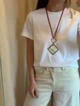 Collar con tiento doble color rojo, aro plateado y dije en forma de rombo con guampa engarzado en alpaca (plateado). Se cierra con cadena de eslabones y ganchito para poder regular unos cm el largo.