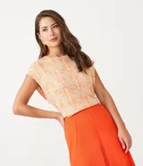 Blusa musculosa de viscosa color durazno con estampado de palmeras en blanco. De corte holgado y cuello redondo.