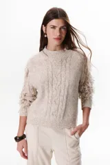 Sweater color beige de tejido de punto con cuello redondo y mangas largas con flecos.