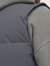 Chaleco acolchado sin mangas color azul marino, con cuello alto y cierre de cremallera.