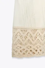 Top blanco de cuello halter con detalle de crochet en el ruedo.