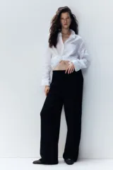 Pantalón negro de corte holgado en tejido de punto con textura. Modelo de tiro alto con cintura elástica y piernas rectas.
