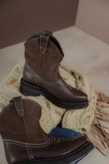 Bota corta de cuero marrón con puntera redondeada, caña alta con detalle de gamuza y costuras decorativas.
