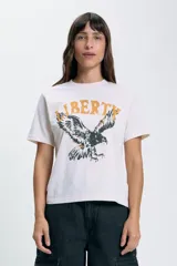 Remera color crudo de corte recto con estampado de un águila y la palabra 'Liberty' en color amarillo.
