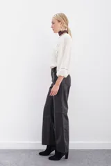 Pantalón de cuero ovino color negro, de corte jeanero con calce oxford y tiro medio. Tiene acceso delantero con botón metálico y cierre, y bolsillos delanteros y traseros.