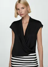 Blusa negra de tejido fluido con diseño cruzado, cuello cruzado y sin mangas.
