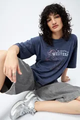 Remerón de manga corta color marrón con efecto lavado y estampa frontal de un caballo con texto estilo western.