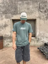 Remera verde oliva de algodón con estampado en la espalda que incluye un símbolo de reciclaje, el logo de la marca Xtreme Wear, la frase 'Breaking Rules' y un texto con tipografía pequeña.