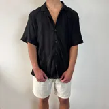 Camisa negra tejida con cuello solapa, manga corta y corte oversize.