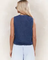 Chaleco de jean azul sin mangas con lazos en el frente.