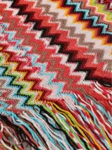 Bufanda larga de tejido suave con diseño de rayas en zigzag multicolor y flecos en los extremos.
