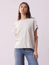 Blusa de lino color blanco con rayas verticales, de la marca Cable & Gauge. Tiene hombros con aplique de botones.