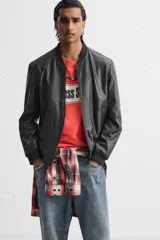 Cazadora bomber negra de efecto piel, corte relaxed fit, con cuello y puños de rib elástico, cierre frontal con cremallera, bolsillos laterales de doble vivo y bolsillo interior.