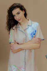 Vestido corto rosado con estampado de flores, cuello solapa, mangas cortas y bordes con puntada overlock en hilo azul.