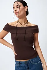 Top tejido color blanco con escote bardot que deja los hombros al descubierto y punto acanalado.