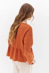 Camisa celeste de algodón con textura arrugada y bordados a tono, escote amplio, mangas largas y botones frontales.