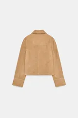 Chaqueta corta de ante color camel, con cuello clásico, cierre frontal con botones, mangas largas y dos bolsillos de parche en la parte delantera.