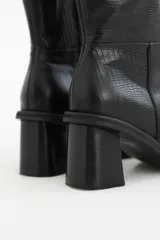Bota corta de cuero color negro, con taco cuadrado y punta cuadrada. Presenta un diseño texturizado imitación piel de reptil.