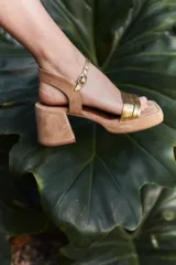 Sandalias de tacón color beige con puntera cuadrada, tiras doradas en el empeine y tobillo, y taco cuadrado.