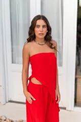 Conjunto de dos piezas color beige claro, compuesto por un top strapless con bajo asimétrico y un pantalón ancho de tiro alto.