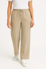 Pantalón de lino color beige, de corte ancho y tiro alto, con bolsillos laterales y cintura elastizada con cordón ajustable.