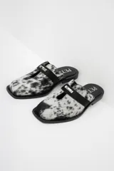 Zuecos con estampado animal print en blanco y negro, con tira ancha de cuero negro y hebilla metálica.
