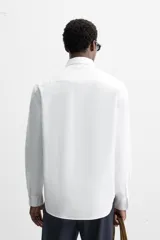 Camisa celeste de algodón, corte relaxed fit, cuello abotonado, manga larga con puños abotonados y cierre frontal con botones.