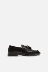 Mocasín de vestir color marrón oscuro, con detalle de borlas en la parte delantera, horma redonda y suela con ligero tacón.