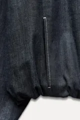 Cazadora bomber de denim color gris oscuro, con cuello redondo, cierre frontal con cremallera metálica, bolsillos laterales y mangas largas con puños elásticos.