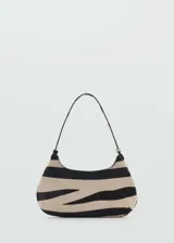 Bolso tipo baguette con estampado de cebra en tonos beige y negro. Tiene asa de hombro y cierre de botón magnético.