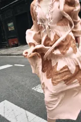 Vestido midi color beige con detalles de encaje marrón, cuello alto con lazo, escote pico, manga larga y botones frontales.