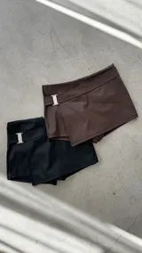 Short pollera de cuero sintético color marrón y negro, con hebilla metálica plateada.